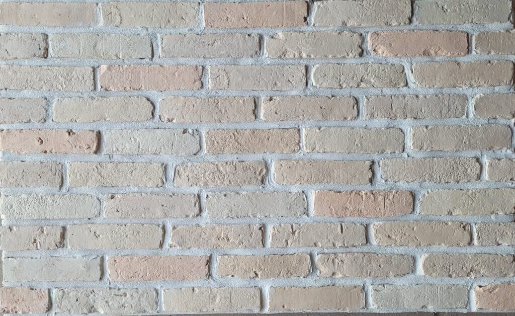Płytki ze starych cegieł na ścianie w odcieniach beżu