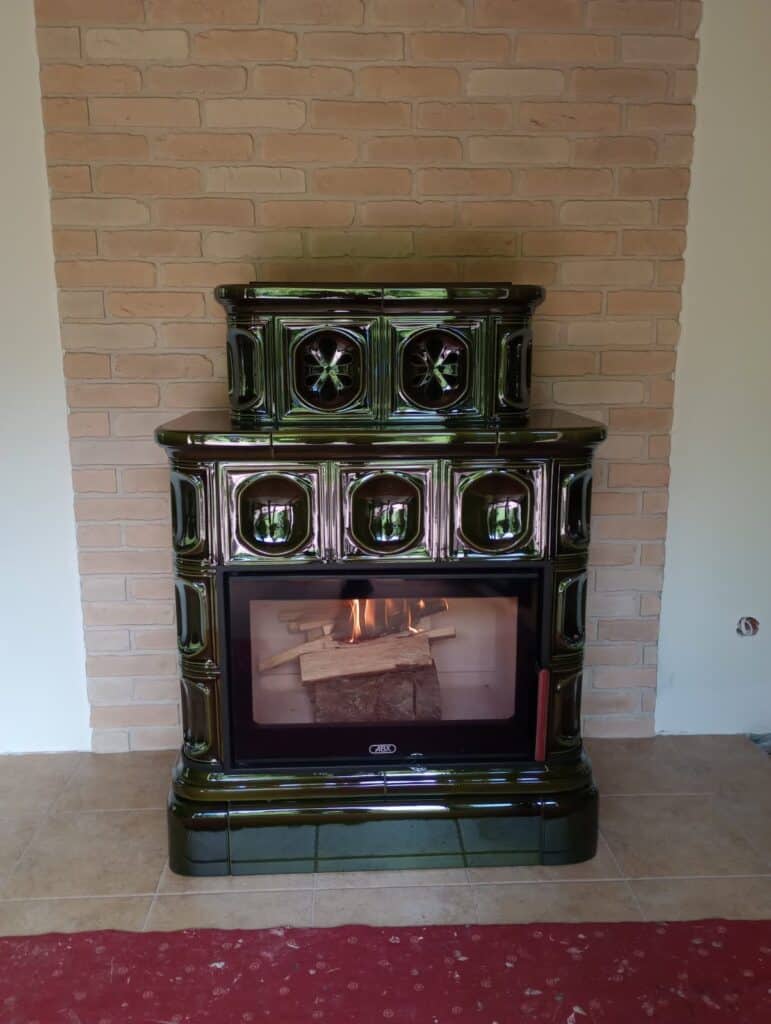 Płytki ceglane ze starych cegieł na ścianie w kolorze piaskowym z kominkiem w kolorze zieleni butelkowej